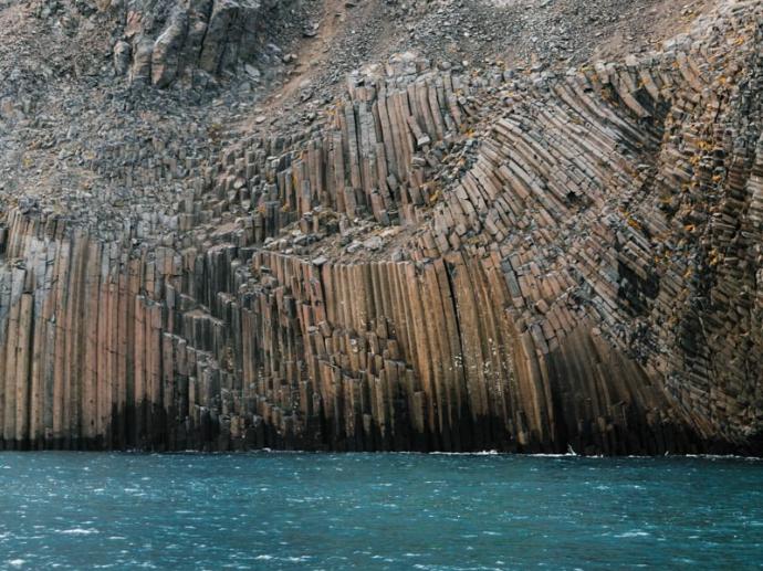 estructura de piedra volcánica enorme con formas laminadas (columnas basálticas prismáticas) sobre el mar